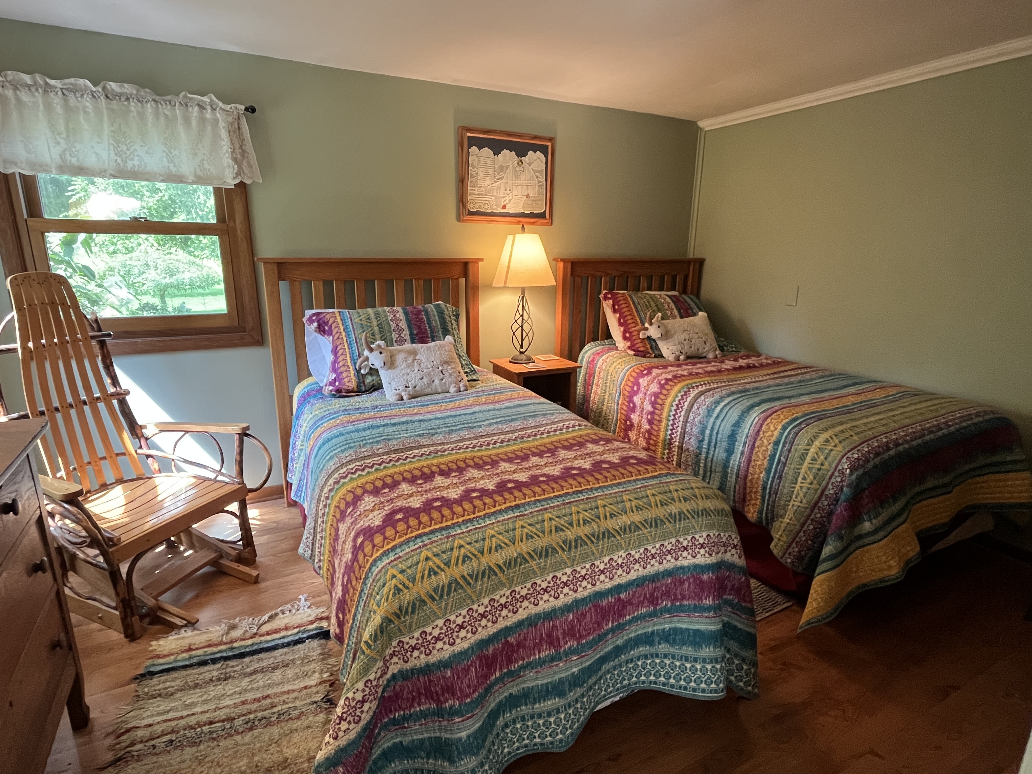 A cozy bedroom with two twin beds, colorful patchwork quilts, and a wooden rocking chair.