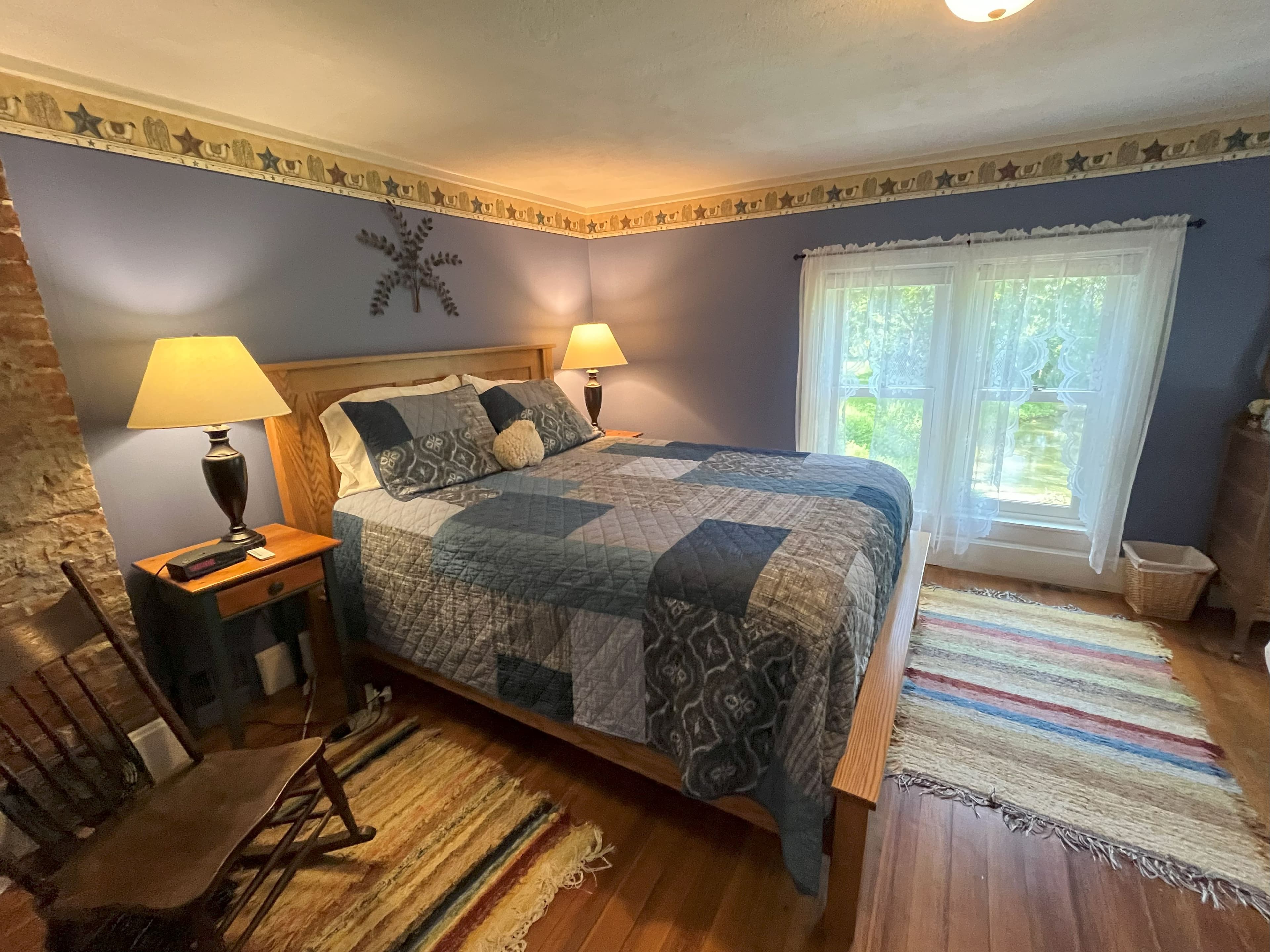 A cozy bedroom with periwinkle blue walls, a patchwork quilt, and a wooden bed frame.